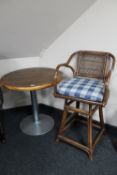 A poser bar table on metal base and a wicker swivel armchair