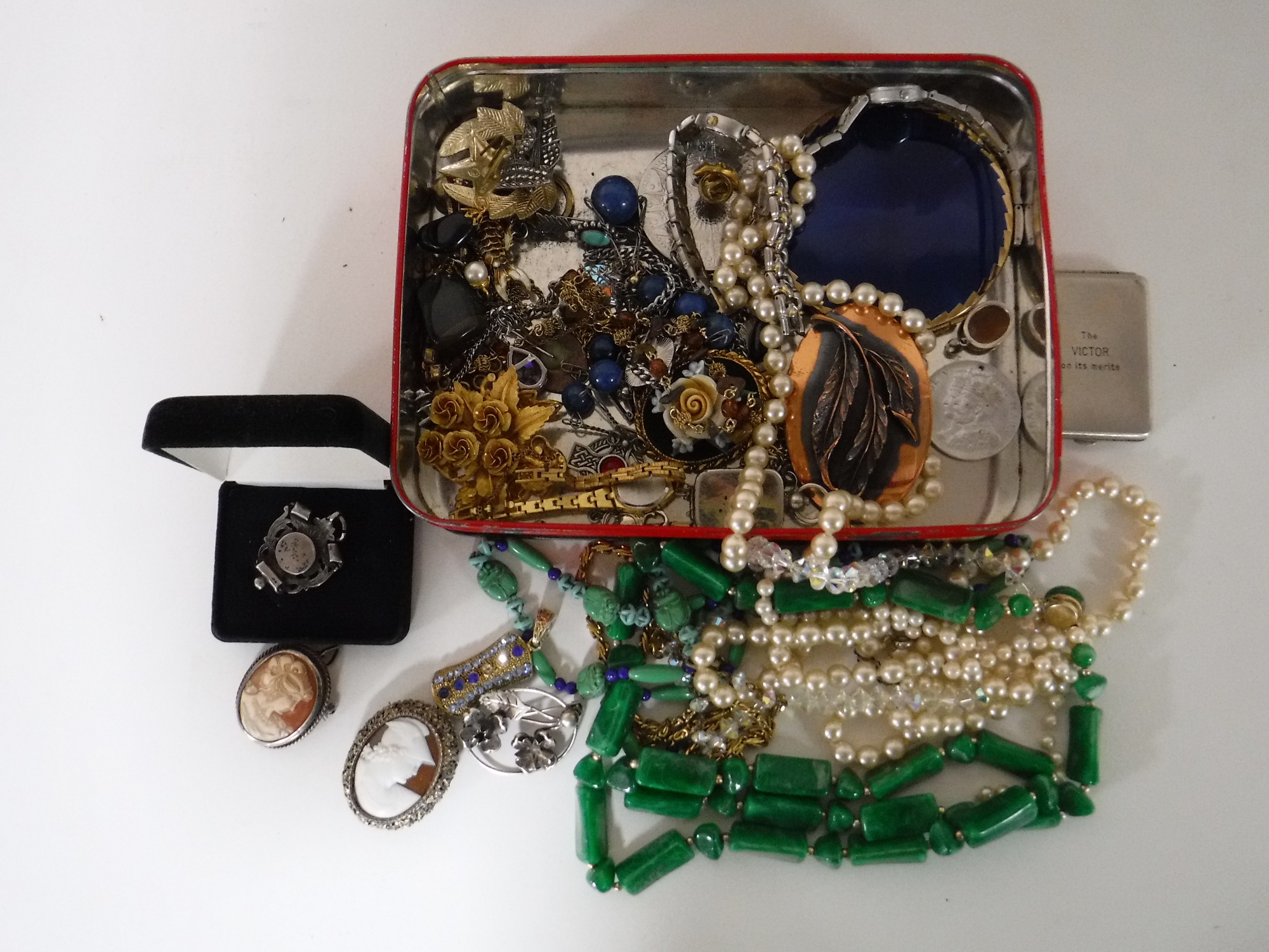 A tin of costume jewellery including silver pieces,