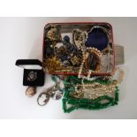 A tin of costume jewellery including silver pieces,