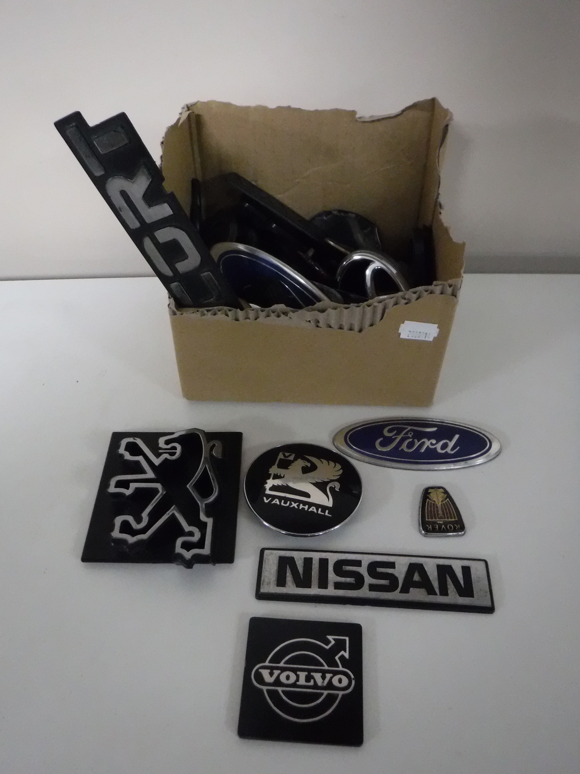 A box containing a quantity of assorted car badges