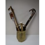 A brass coal bucket containing walking sticks, umbrella,