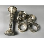 Seven silver items including a small vase, pepperette and five napkin rings.