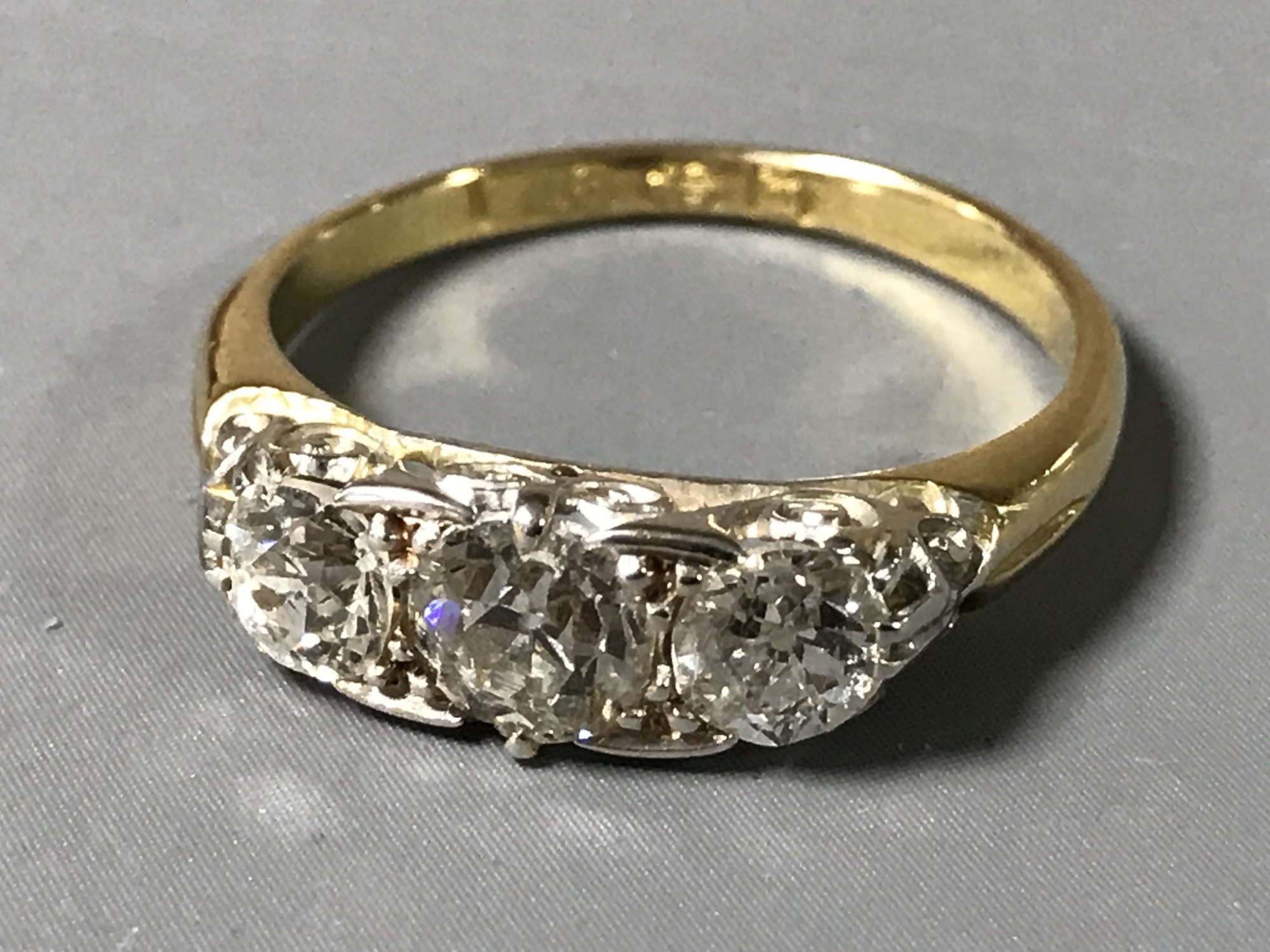 A Victorian diamond ring, set with three round old cut diamonds, the largest approximately 4.