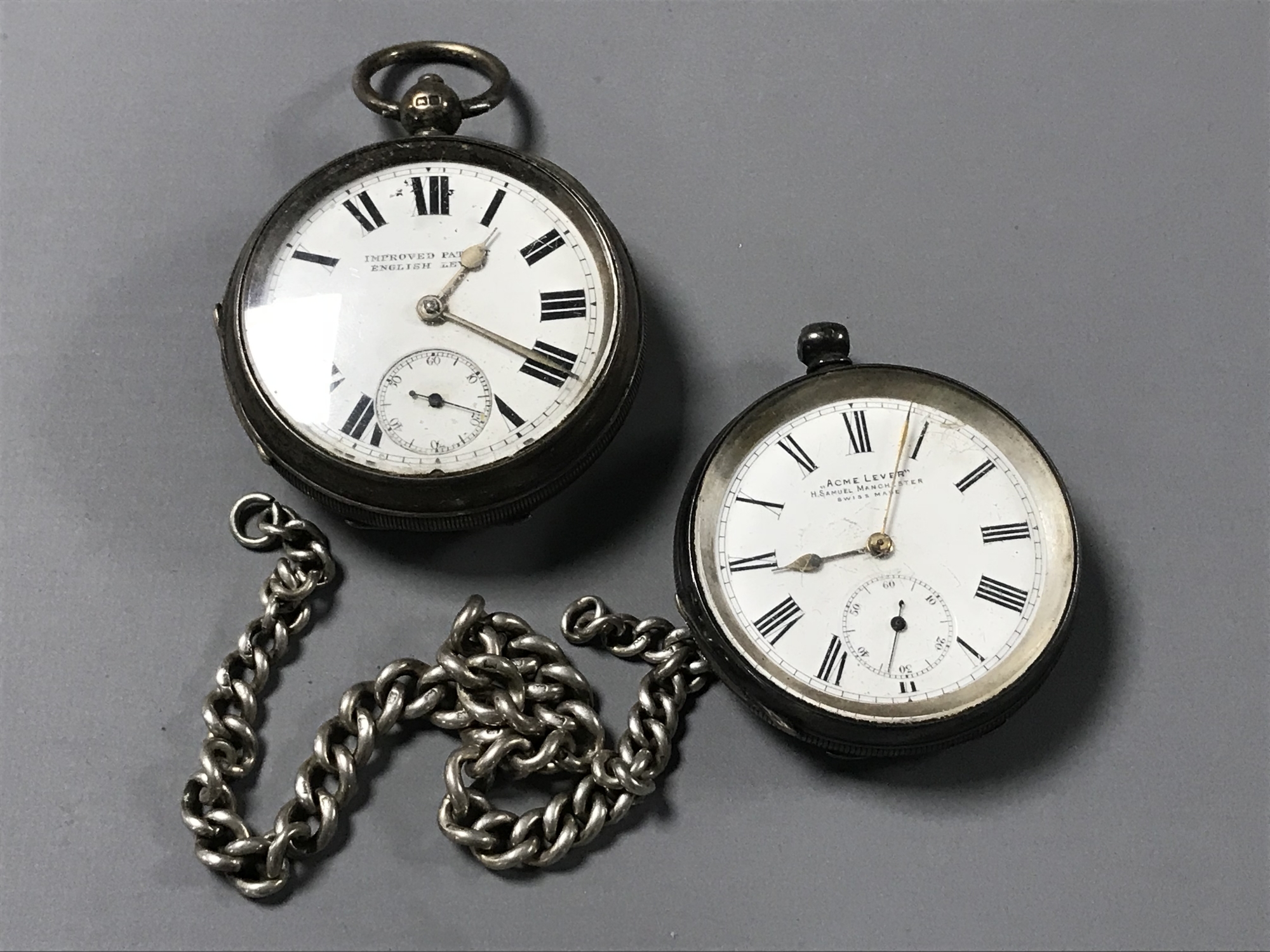 Two silver pocket watches and a silver watch chain.