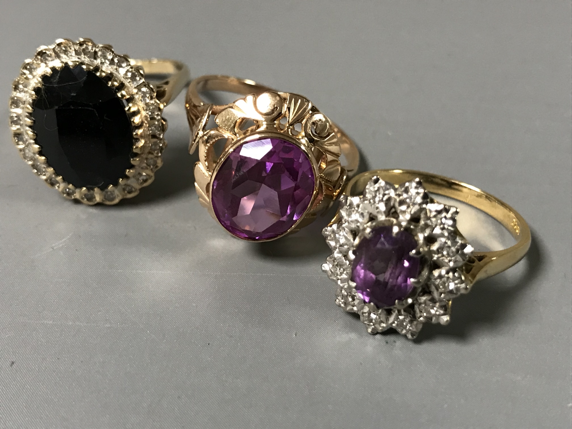 Three gold rings - An 18ct gold pink stone ring 4.9g, an 18ct gold amethyst and diamond cluster 4.