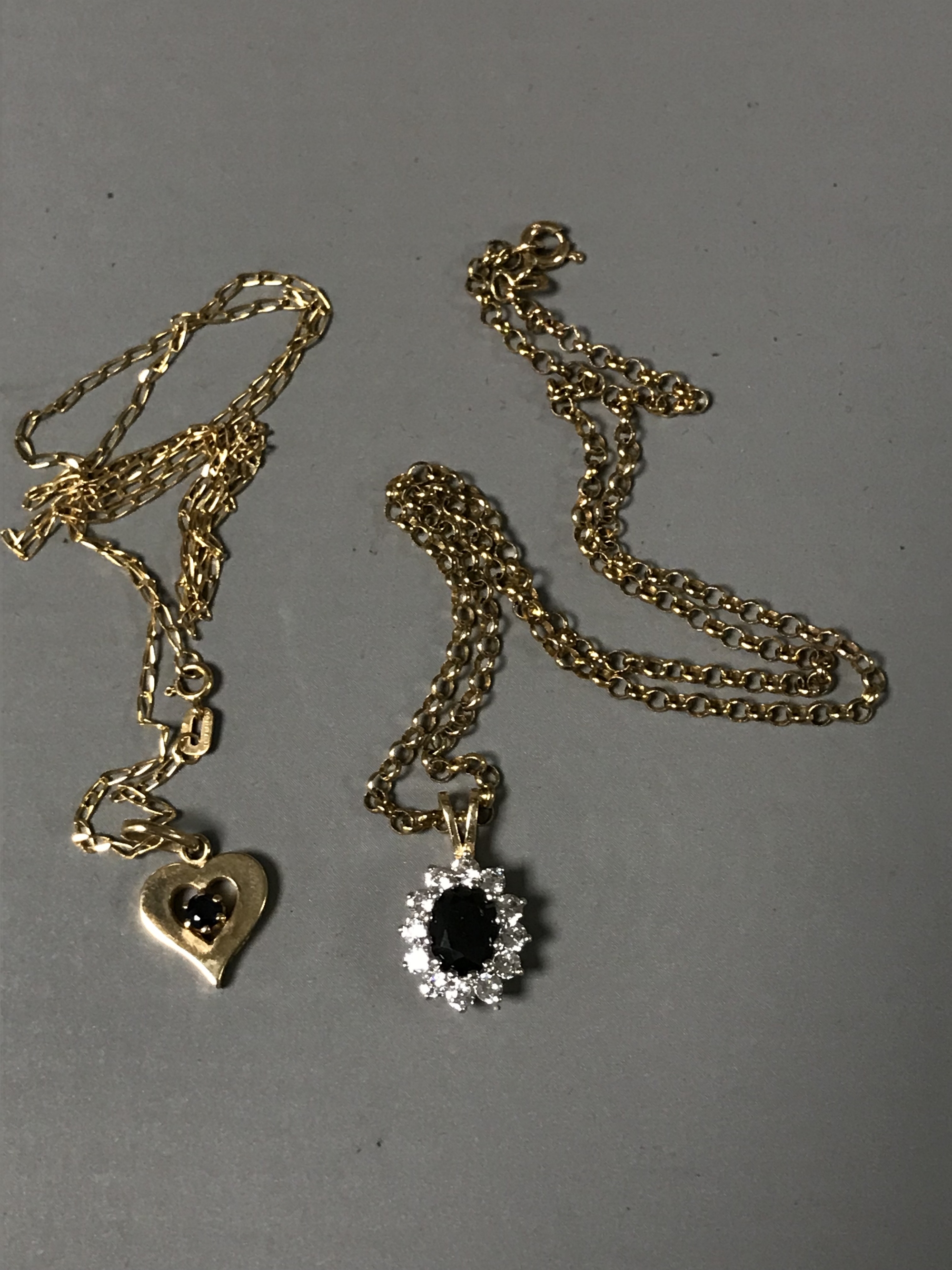 Two 9ct gold pendants and chains set with sapphires.