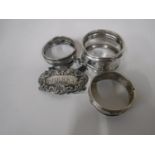 A silver sherry label and three silver napkin rings