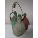 Three antique green glass bottles in wicker covers