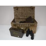 A wicker basket containing five pairs of binoculars and three binocular cases and two metal