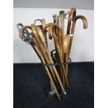 A cast iron stick stand, containing a quantity of walking sticks,