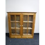 A pine glazed double door wall cabinet,