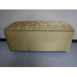 A large blanket box upholstered in a gold button fabric
