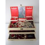 A cream leatherette jewellery box containing assorted costume jewellery, simulated pearls,