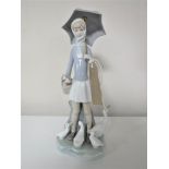 A Lladro figure of a girl holding an umbrella surrounded by ducks