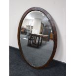 A large oval Edwardian oak framed bevel edged mirror