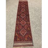 A Persian carpet runner on red ground,