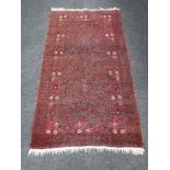 A fringed woolen Persian rug on red ground