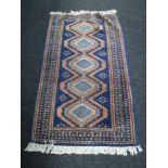 A fringed woolen rug of geometric design on blue ground
