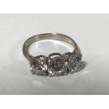 An 18ct white gold three stone dress ring, size N.