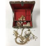 A casket jewellery box containing assorted costume jewellery including two gold and silver rings,