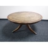 A circular mahogany coffee table on brass inlaid pedestal