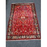 A fringed Turkish woolen rug on red ground