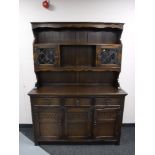 A carved oak triple door kitchen dresser