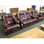 A wood framed burgandy button leather three piece lounge suite