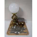 A tray containing a brass oil lamp with glass shade, converted, assorted table cutlery,
