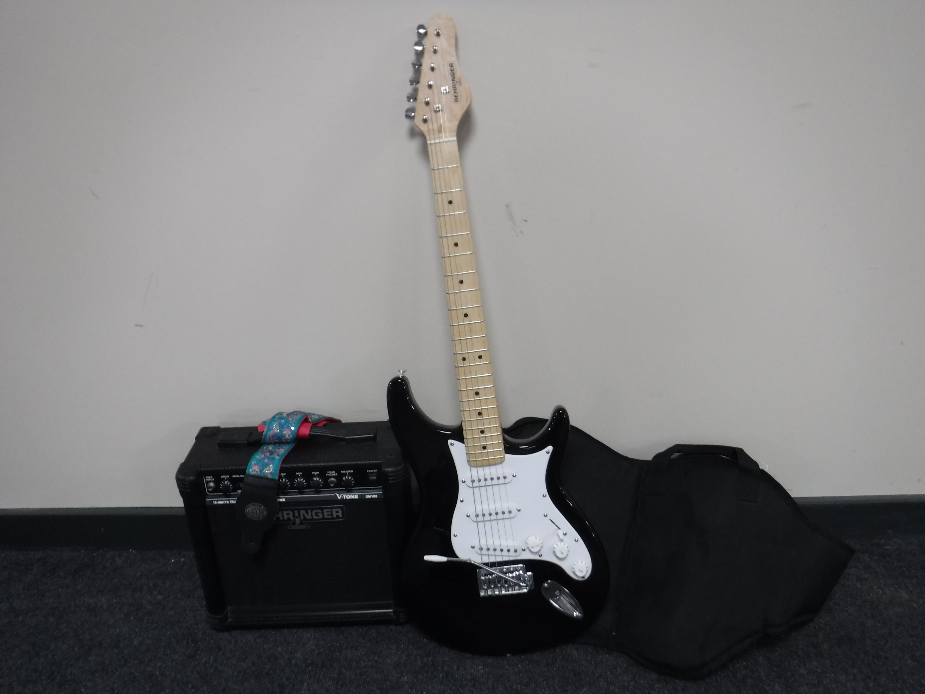 A Behringer electric guitar in carry bag with amp