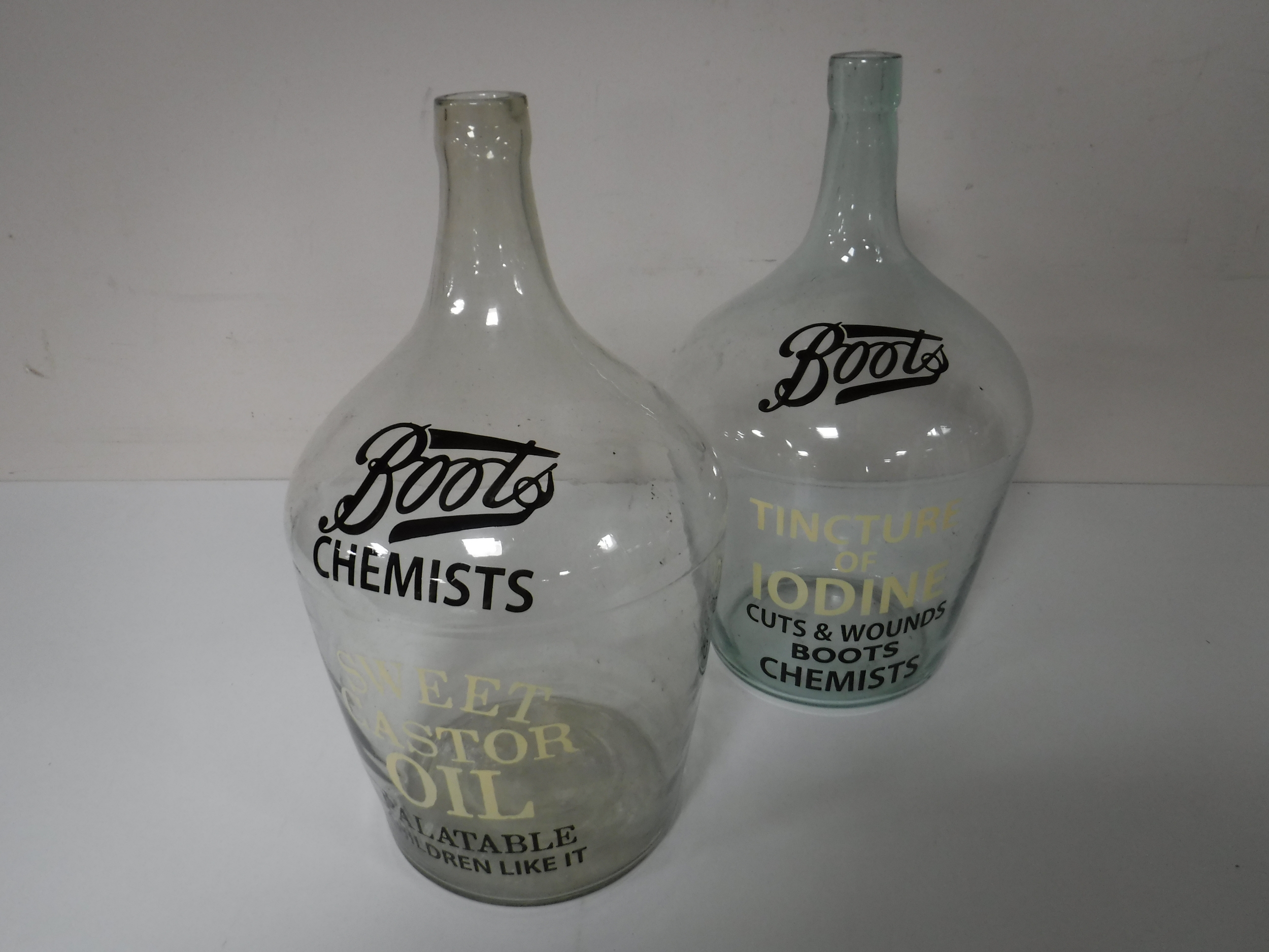 Two glass demijohns bearing Boots chemists advertising