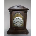 An early twentieth century oak cased mantel clock with brass and silvered dial