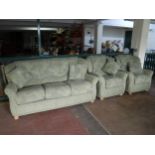 A three piece lounge suite upholstered in green fabric on bun feet and scatter cushions