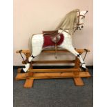 A painted wooden rocking horse on pine stand