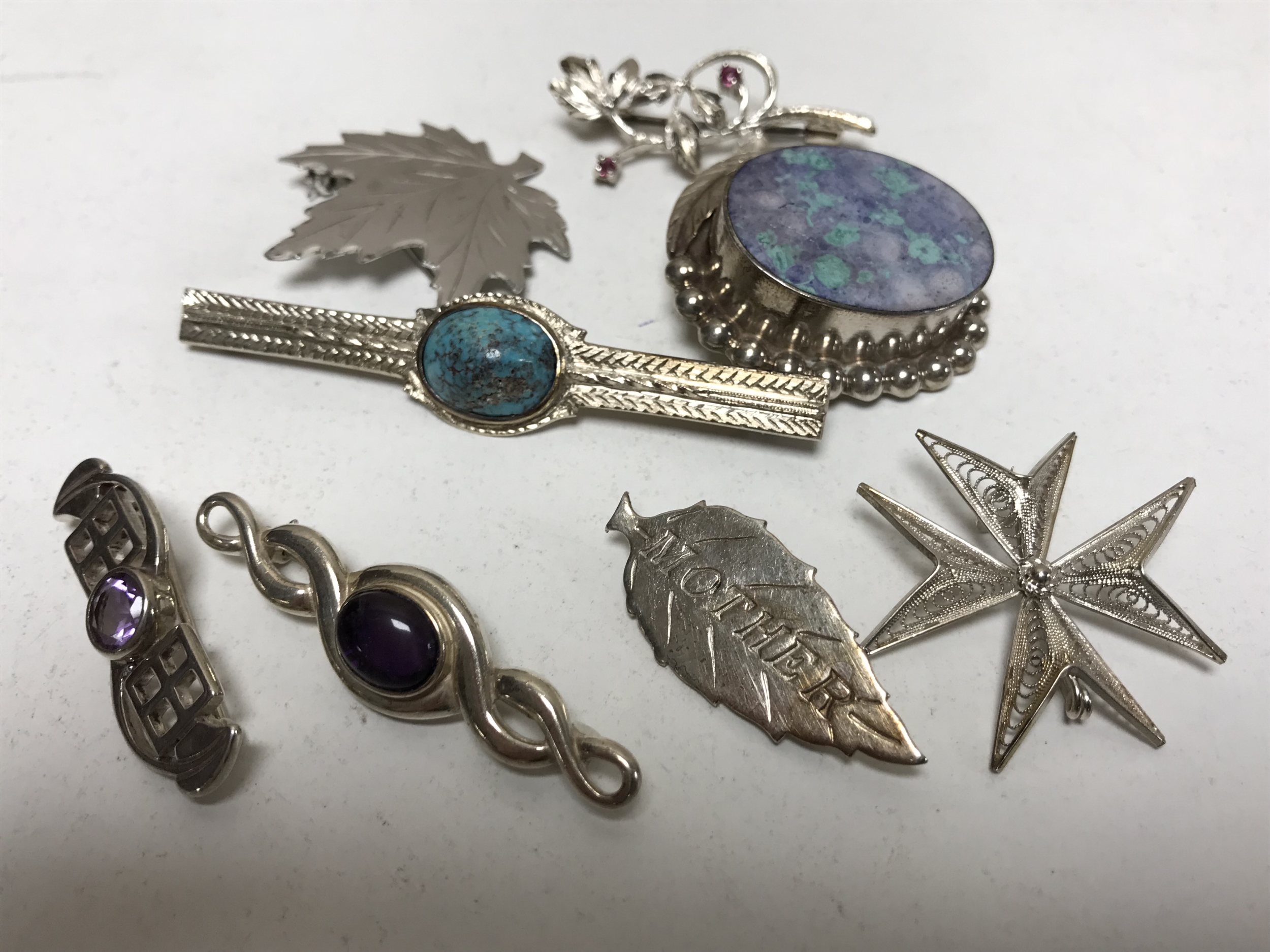 A collection of silver brooches