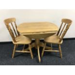 A contemporary pine effect drop leaf kitchen table together with two chairs