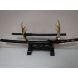 Two reproduction samurai swords on antler stand