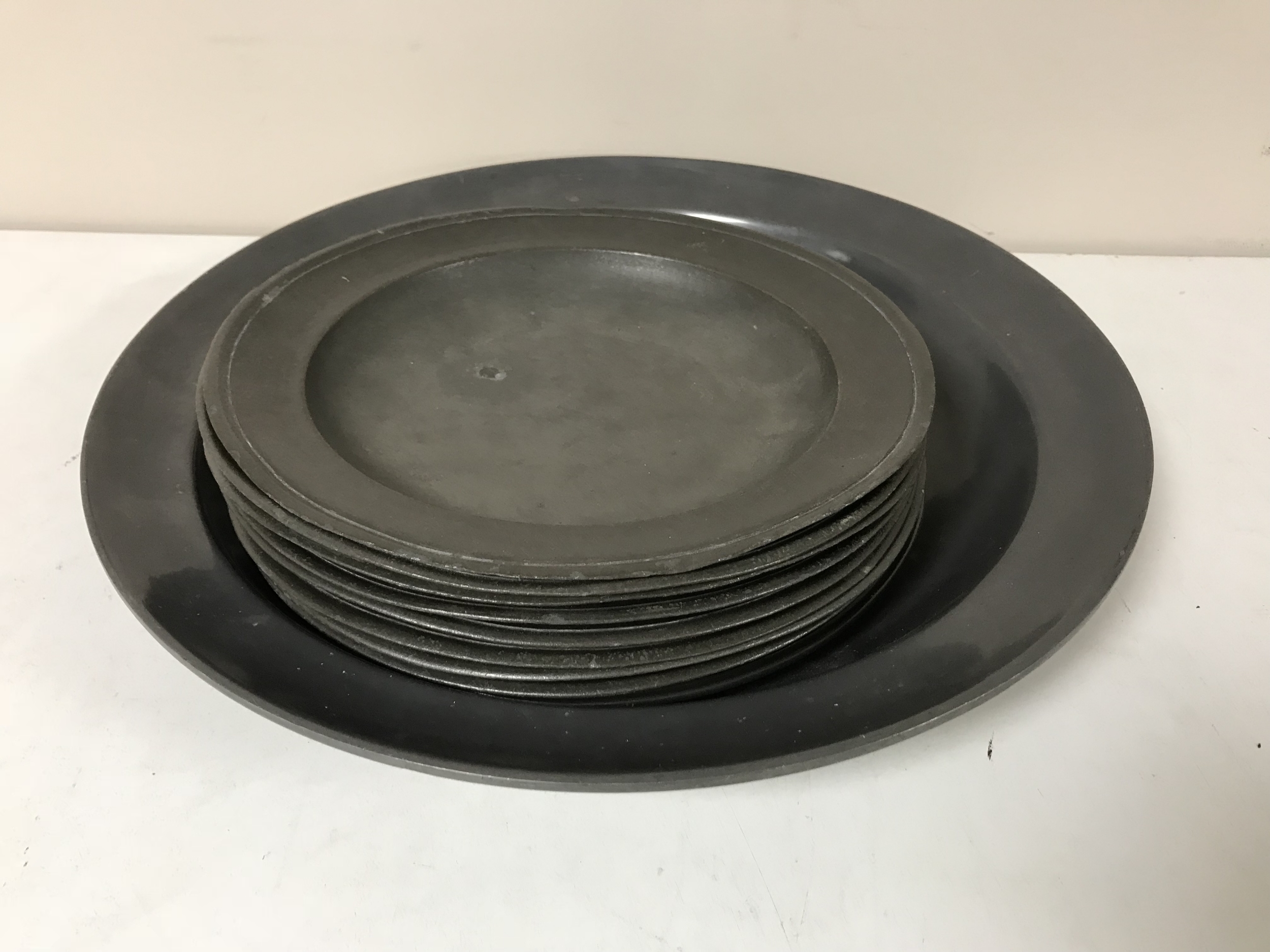 Nine antique pewter plates together with a large pewter charger