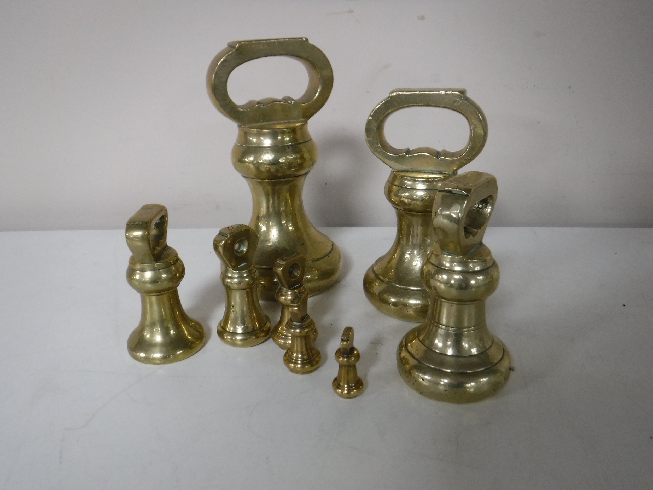 A set of eight graduated antique brass weights