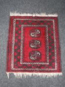 A small fringed Persian hearth rug on red ground