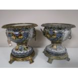 A pair of glazed pottery bowls on gilt metal stands with rim and lion mask handles