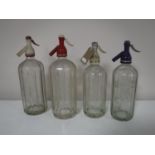 Four vintage glass soda siphons bearing advertising Schweppes,