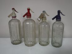 Four vintage glass soda siphons bearing advertising Schweppes,