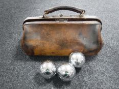A vintage leather bag containing a set of French boules