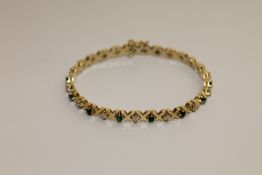 An 18ct gold line bracelet, set with alternating emeralds and diamonds between X-shaped links,