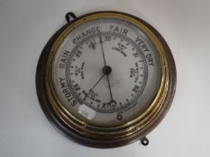 A circular brass barometer mounted on board