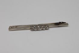 An 18ct white gold and platinum set five stone diamond bar brooch, approximately 0.7ct, 5.2g.