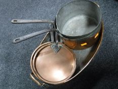 An antique copper twin-handled oven dish and two cast iron pans with lids