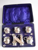 A cased seven piece sterling silver cruet set and five spoons with glass liners