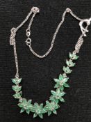 An emerald floral necklace on silver chain